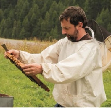 Gian Luca Giacomo Garnero che guarda un telaietto di un alveare con la tuta dell'epicoltore