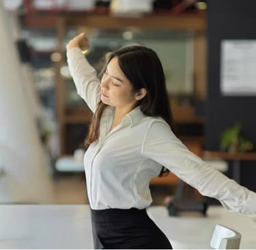 Business woman in white shirt stretching at her office desk to relieve stress and back pain.