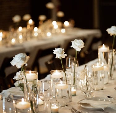 Mesas para evento decorada con manteles, llena de platos, tenedores, y otra decoracion