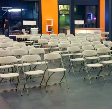 Sillas blancas plegables para eventos corporativos en el paso