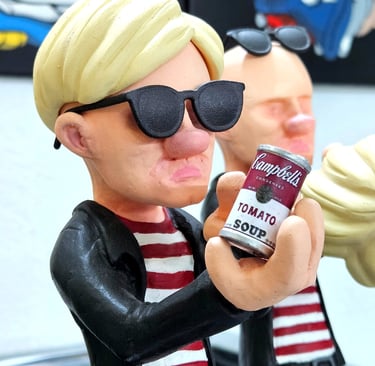 Andy Warhol caricature figurine wearing sunglasses and holding a miniature Campbell's tomato soup can.