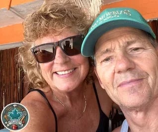Jo Schultz smiling, wearing sunglasses hugging behind her husband