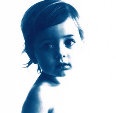 Monochromatic blue portrait of a little girl with short, tousled hair, expressive eyes, and a serene