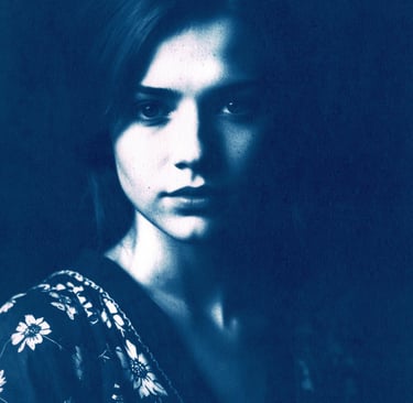 Close-up portrait of a young woman with fair skin, long straight hair, and soft lighting highlightin