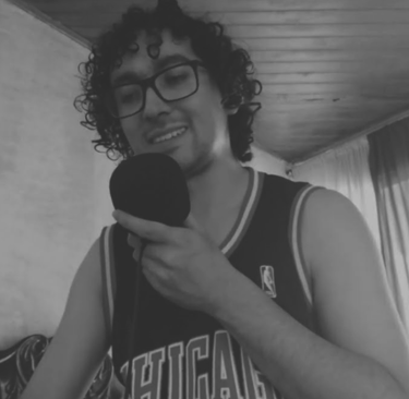 Hombre con gafas y camiseta deportiva hablando frente a un micrófono.