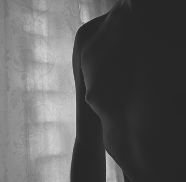 Hombre artístico de cuerpo humano en blanco y negro frente a una cortina floral.
