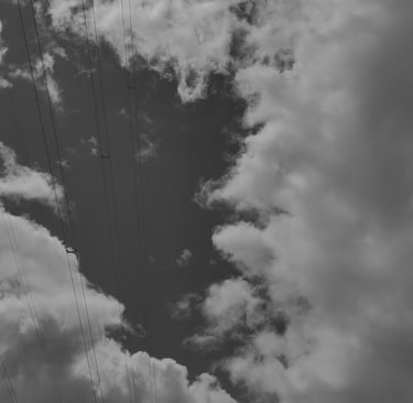 Cielo nublado en blanco y negro con cables de alta tensión. Fotografía urbana minimalista.