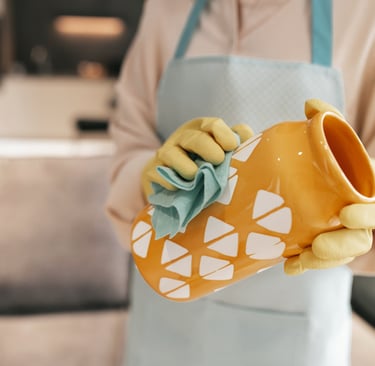 a person in a apron and gloves cleaning a cup