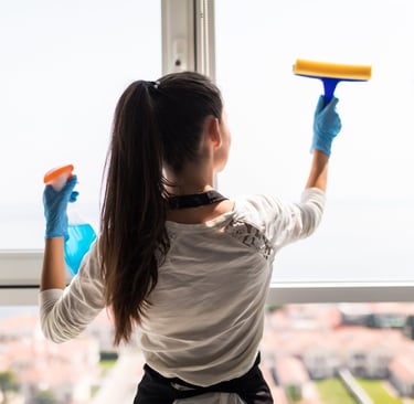 a woman in a white shirt and gloves holding a blue cleaning sponge