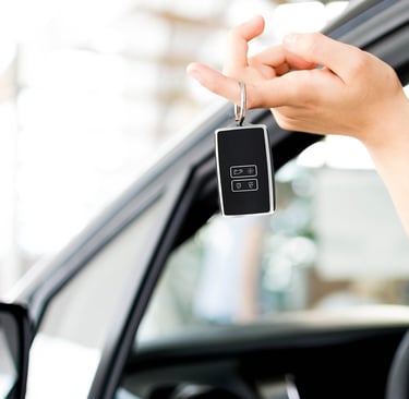 Vrouw die hand uit auto steekt met in haar hand een sleutelhoesje.