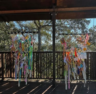 Two large netted frames with colourful fabric and paper artworks woven into them. 