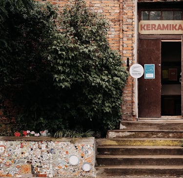 Old red brick house with open doors. On top of it is written: ceramics. 