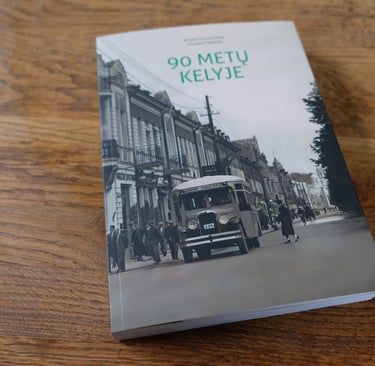 Cover of the book "90 Years on the Road". The photo on the cover shows a vintage bus driving along Laisvės Alėja. 