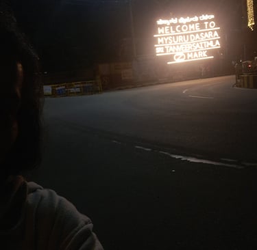 This is the author at the entry of Mysuru with "Welcome to Mysuru" written in background with lights