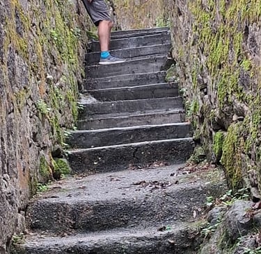 person on narrow steps between high walls