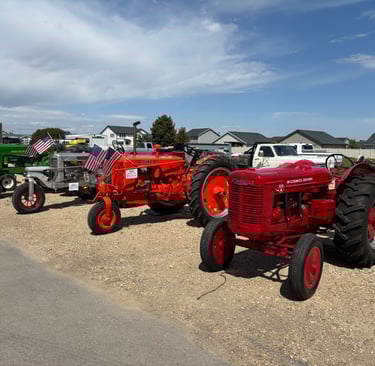 a row of tractors parked in a gravel lot