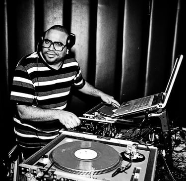 DJ Rico Sanchez wearing headphones mixing vinyl records on turntables in a club setting