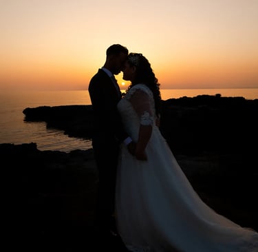 una sposa e uno sposo che si baciano davanti al tramonto
