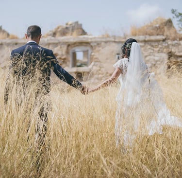 una sposa e uno sposo che si tengono per mano in un campo 