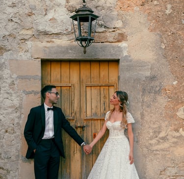  una sposa e uno sposo che si tengono per mano davanti un'antica porta siciliana