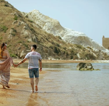 un uomo e una donna che si tengono per mano e camminano su una spiaggia