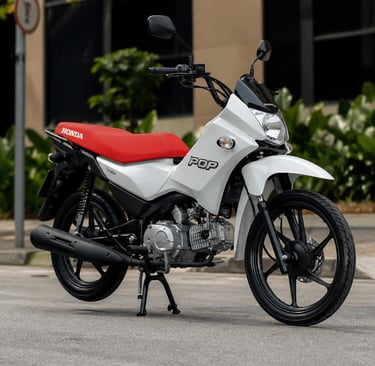 Moto Honda Pop 110i branca com banco vermelho estacionada em rua urbana, com árvores e prédios ao fu