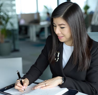 a woman in a suit is writing on a notebook