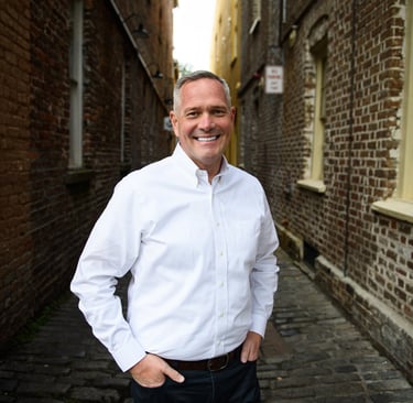 a man in a white shirt and jeans standing in an alley alleyway