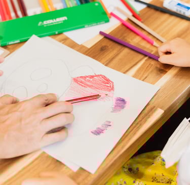 a child's hand is drawing a heart with colored  at Kinntorpencils