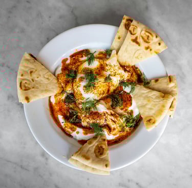 a bowl of thick yoghurt with pitta bread and dill herbs