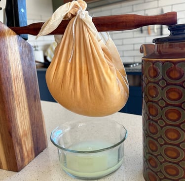 straining yoghurt in a cheese cloth hanging on a rolling pin