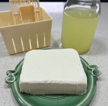 thickened yoghurt, a jar of whey and a strainer mould