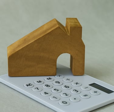 Un bloc en bois sculpté en forme de maison posé sur une calculatrice blanche, avec une vue rapproché