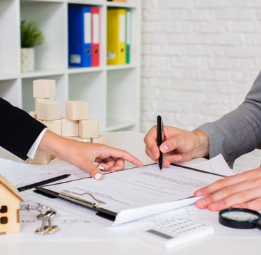 Signature d'un contrat immobilier avec une maquette de maison et des documents sur la table.