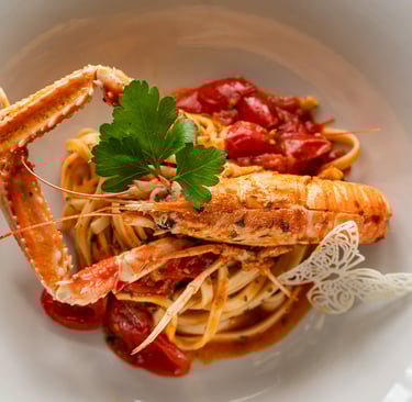 Tagliolini con scampi, pomodorini e prezzemolo in piatto bianco, guarnite con decorazione