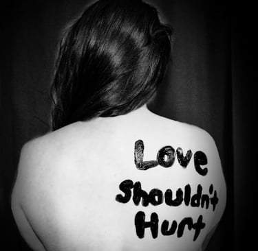 a woman domestic violence survivor with the words love shouldn't hurt on her back