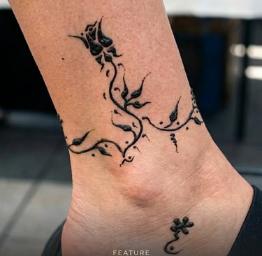 A detailed black henna floral anklet tattoo design on a person's ankle.