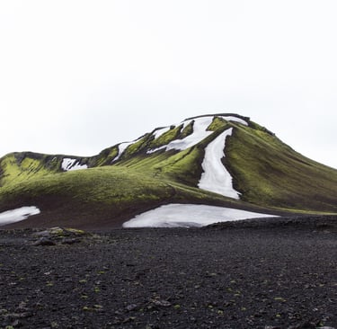 A green mountain with ice falling from the top.