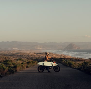 A scenic background with mountains and oceans. A person riding motorbike and scateboard toward it 
