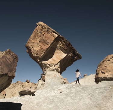 Rocky background with clear sky and a person walking towards unknown direction.