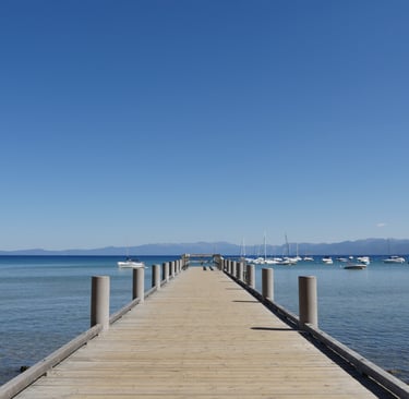 A brige leading to a ocean with boats on background