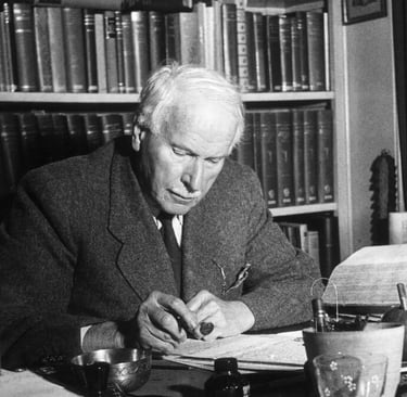 A black and white potrait of Swiss psychatrist Carl Jung sitting in his office writing something.