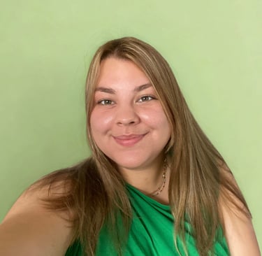 Glimlachende vrouw met lang bruin haar in groene top tegen zachte groene achtergrond.
