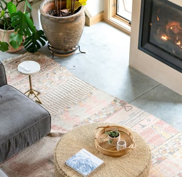 boho style living room with a rattan table, textured area rug, fireplace, ceramic potted plants