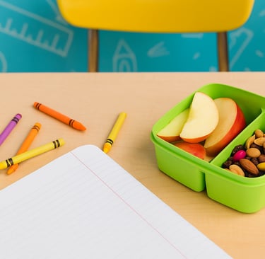 Child’s school desk with crayons, notebook, and a healthy snack of apple slices and trail mix.