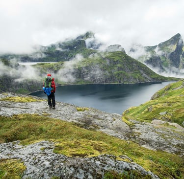 person hiking in the moutains looking down at a lake