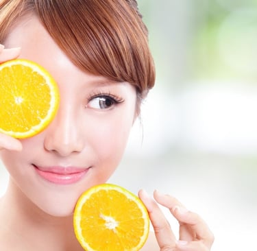 vitamine c serum, vrouwelijk model en een sinaasappel