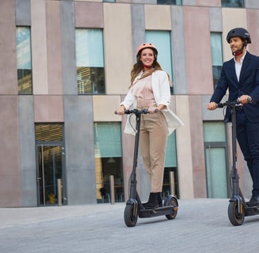 a man and woman riding scooters on a city street