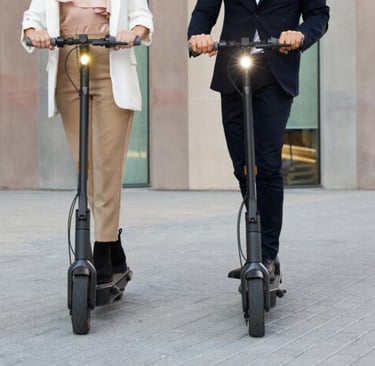 a man and woman riding scooters on a city street