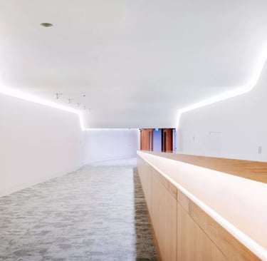 Modern minimalist white hallway with LED cove lighting and wooden wall paneling.